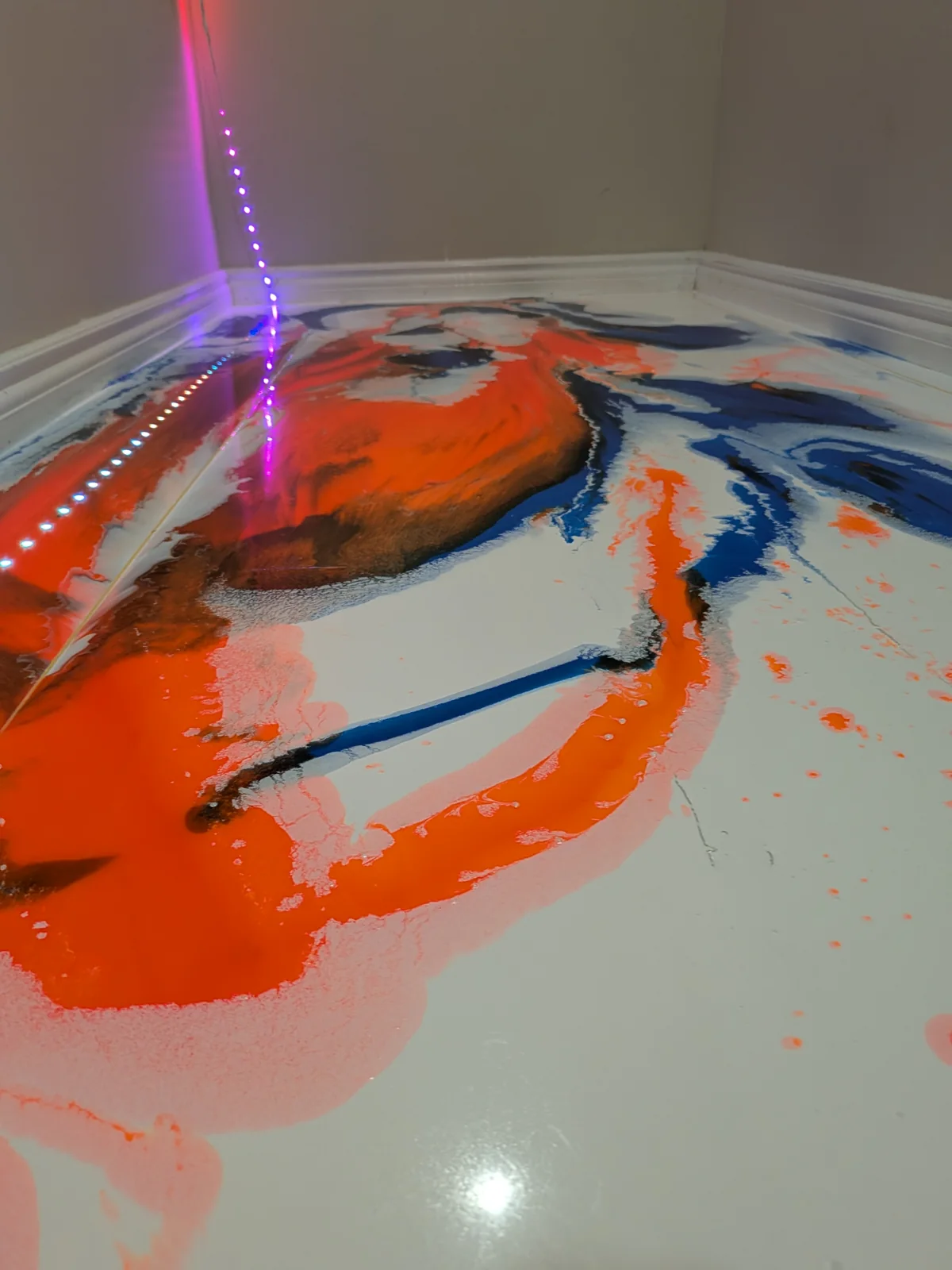 Orange, blue and black fluid epoxy pattern over a white floor
